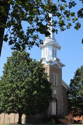 A sunlit view of Marvin United Methodist Church's brick facade surrounded by green trees.