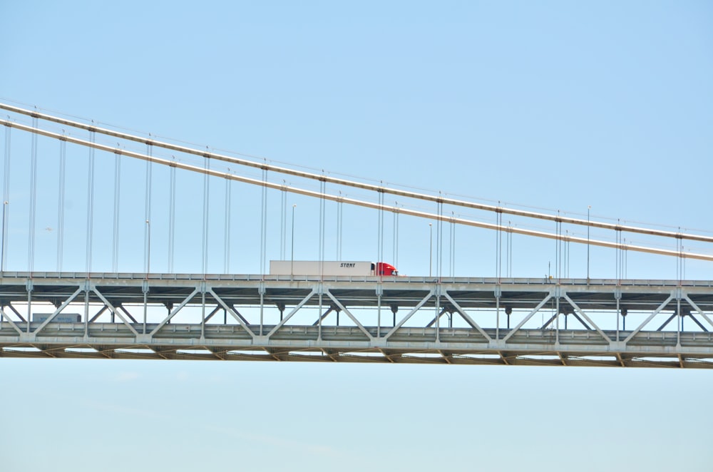 a red truck driving across a bridge over water