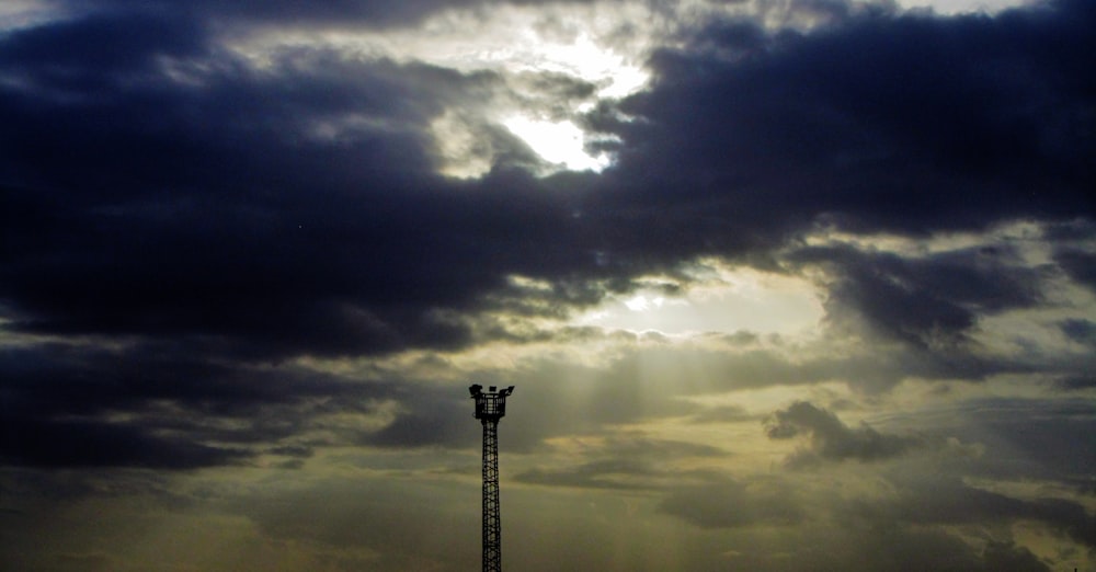 a tall light pole under a cloudy sky