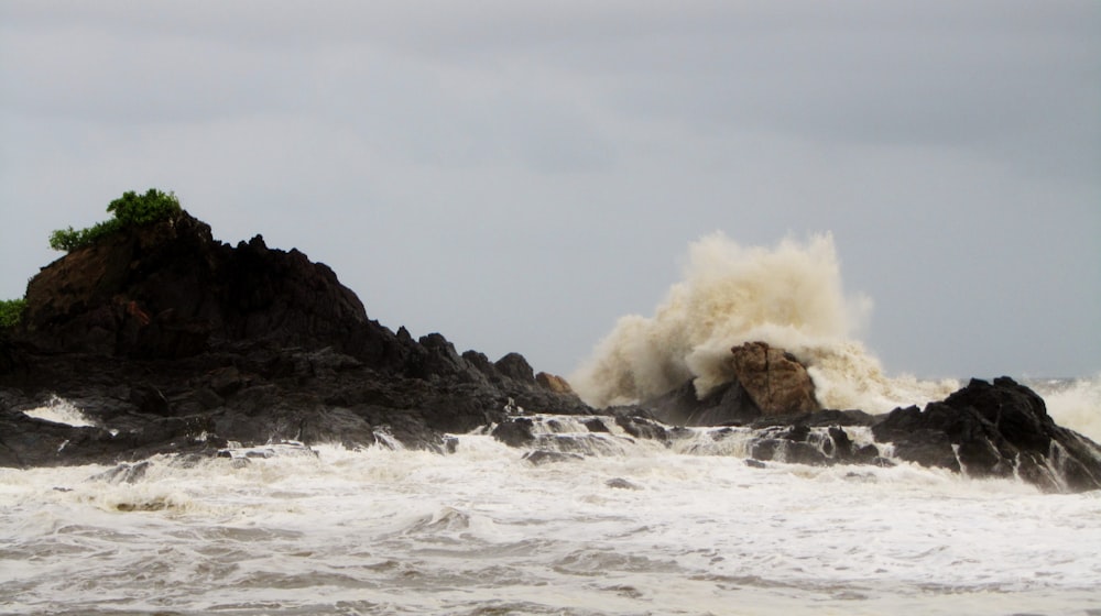 a large wave crashes against a rocky shore