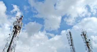 a group of cell towers sitting under a cloudy blue sky