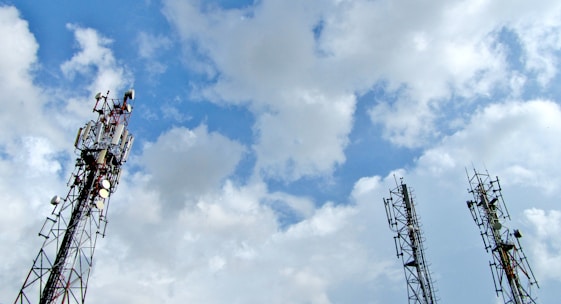 a group of cell towers sitting under a cloudy blue sky