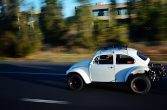 Black and white photo of a classic Volkswagen TL cruising past, evoking rock and roll spirit.