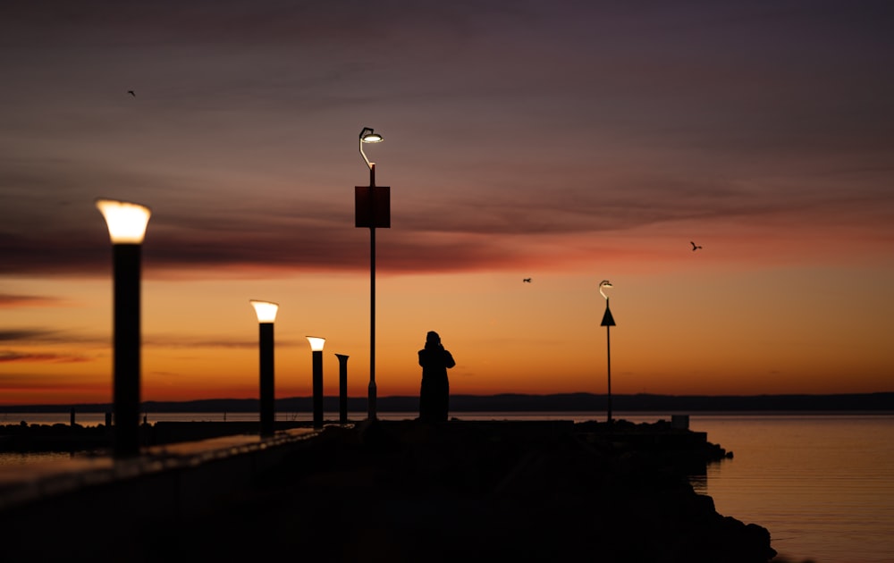 a person standing on a pier at sunset