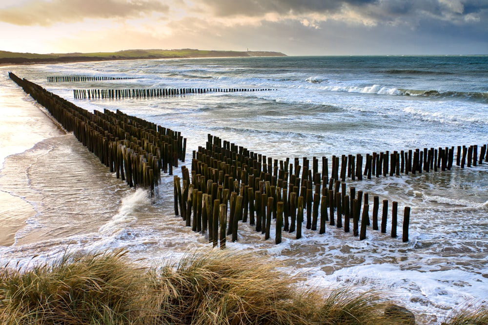 a wooden fence sitting on top of a beach next to the ocean