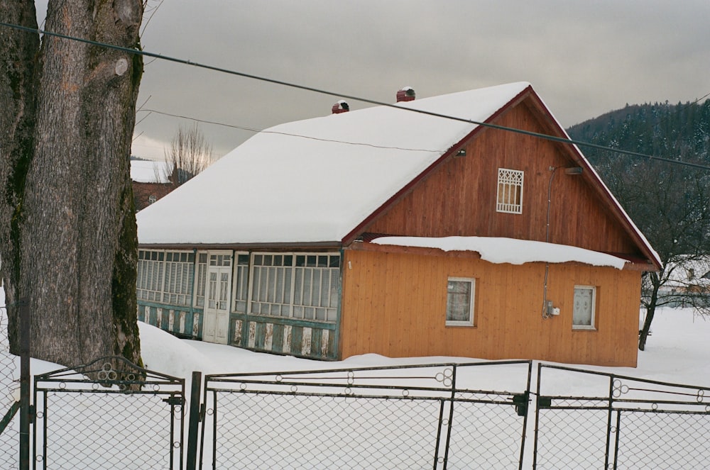 a house is covered in snow behind a fence