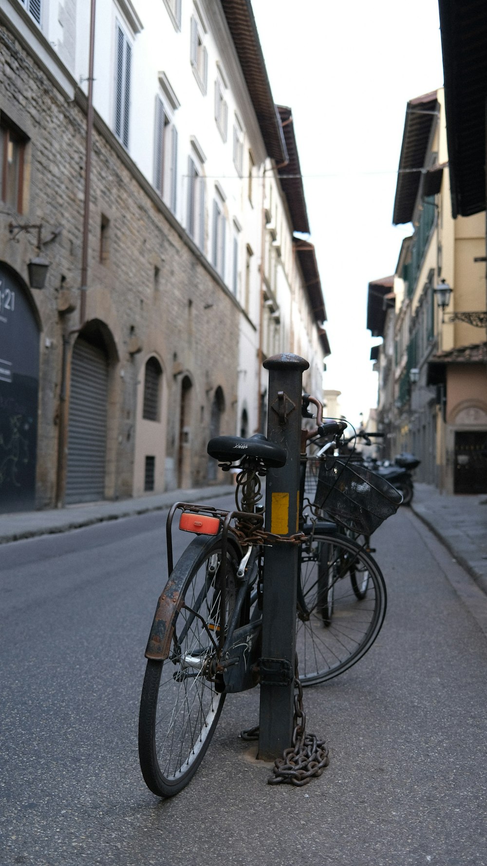 a bike chained to a pole on the side of a street