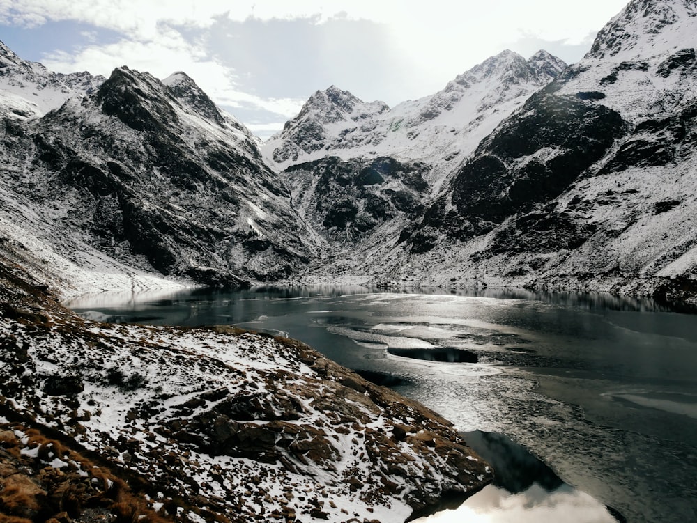 a snow covered mountain range with a lake in the foreground