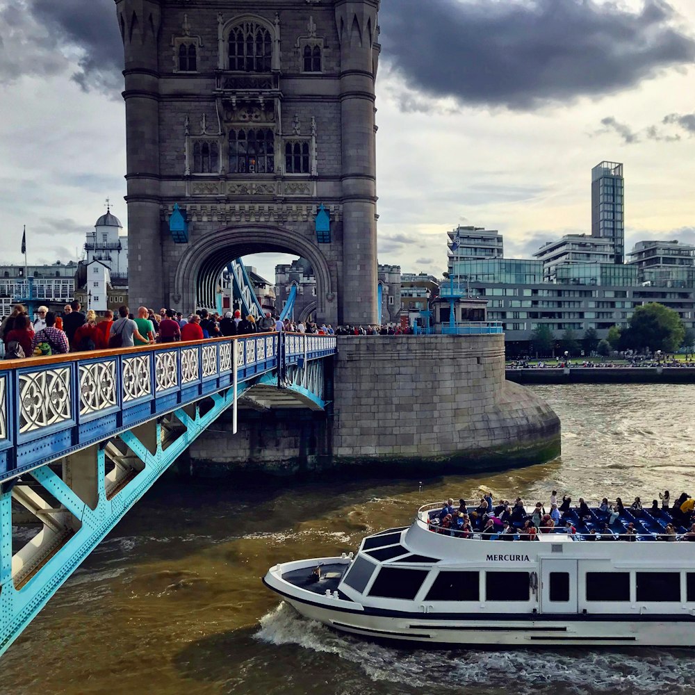 a boat full of people going under a bridge