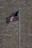 A proud homeowner standing beside a tall, gleaming flagpole with an American flag waving in the breeze.