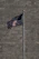 A proud homeowner standing beside a tall, gleaming flagpole with an American flag waving in the breeze.