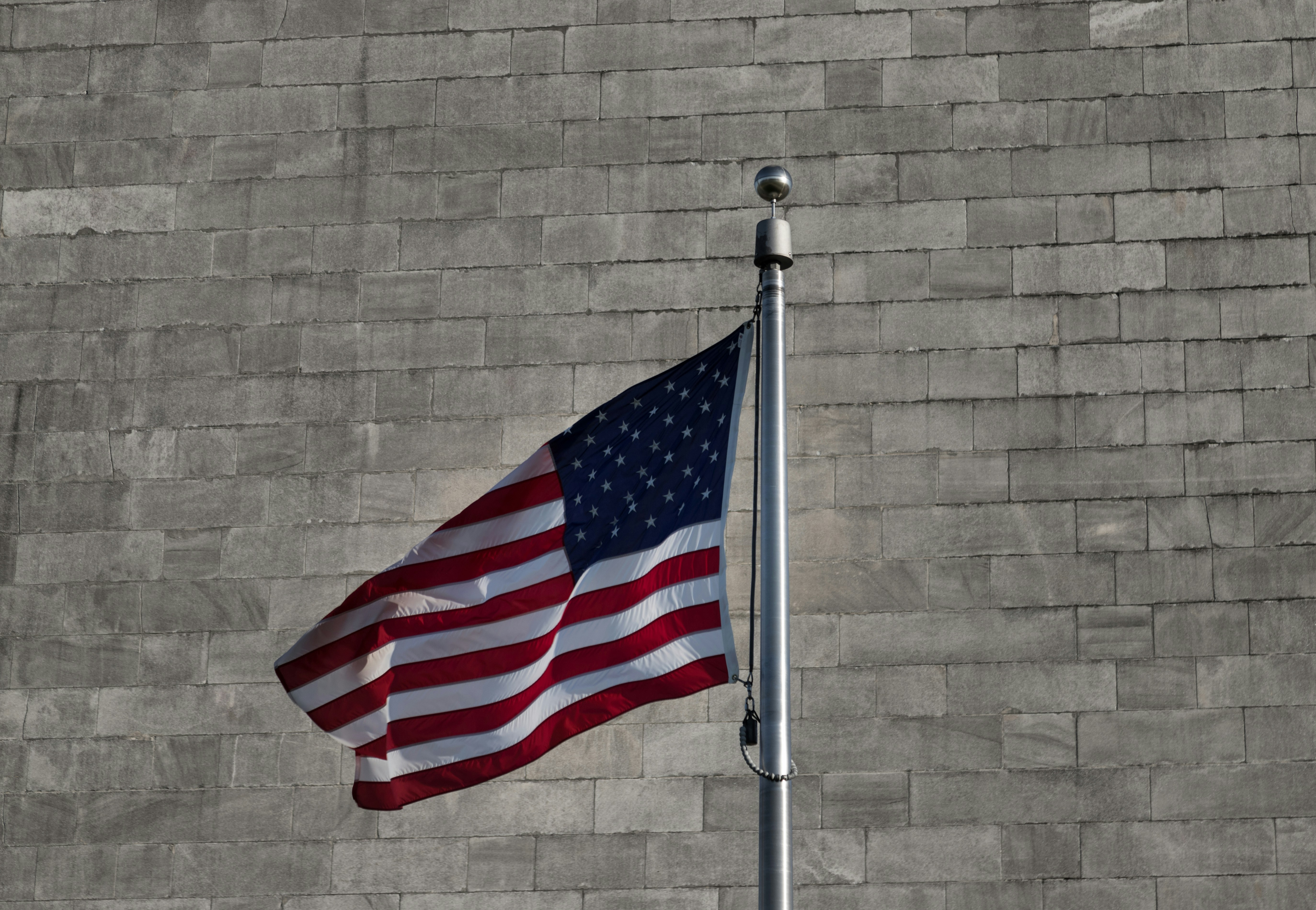 an american flag is flying in front of a brick wall