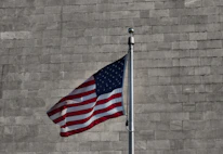 an american flag is flying in front of a brick wall