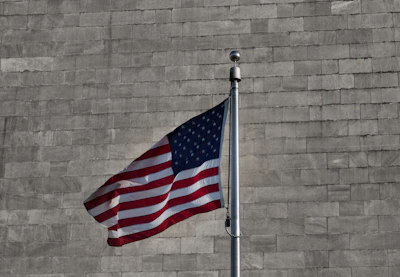 an american flag is flying in front of a brick wall