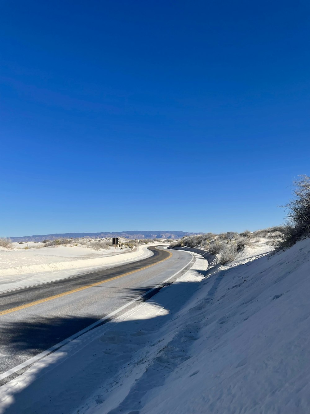 a snow covered road with a blue sky in the background