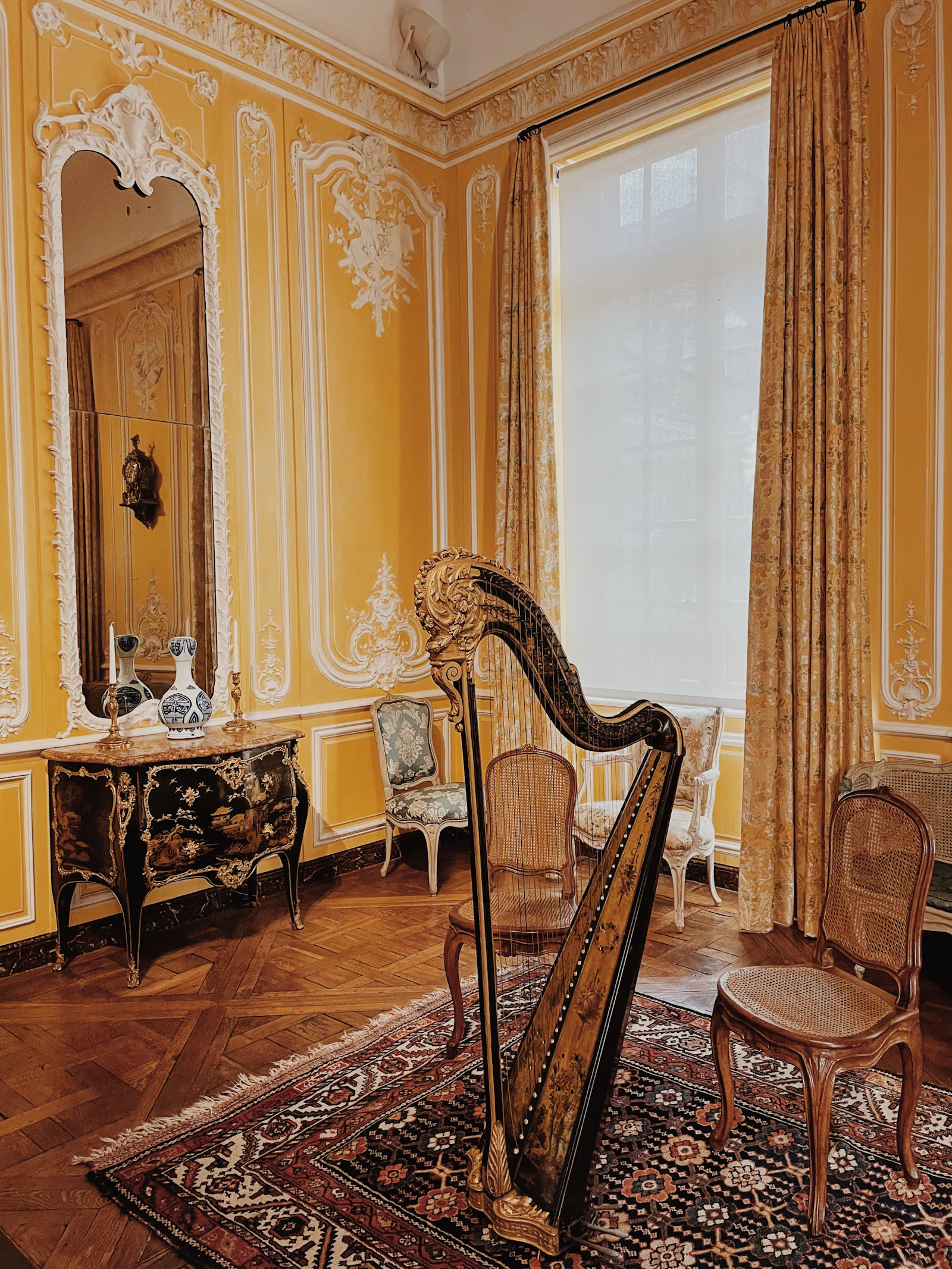 A harp standing on a rug in a high ceilinged room.
