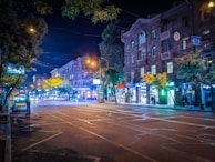Nighttime street view with illuminated storefronts and people walking by.