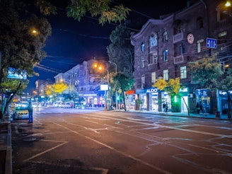 Nighttime street view with illuminated storefronts and people walking by.