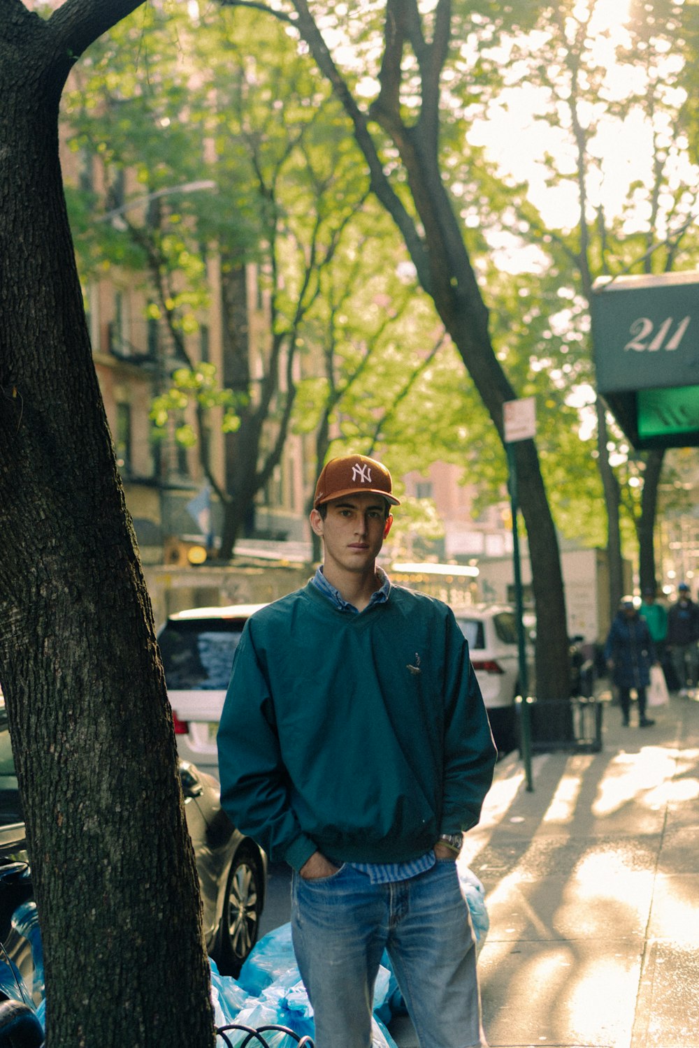 a man standing next to a tree on a sidewalk