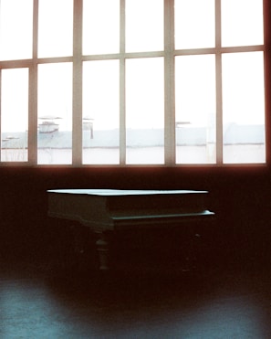 Warmly lit room with a piano and a single spotlight highlighting the instrument.