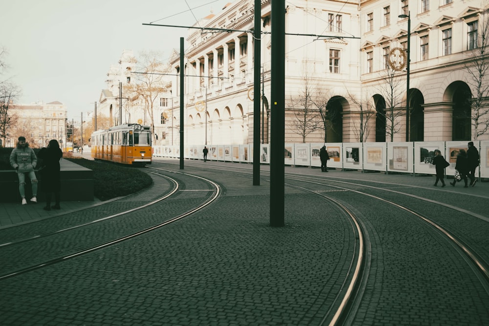 a yellow train traveling down train tracks next to a tall building