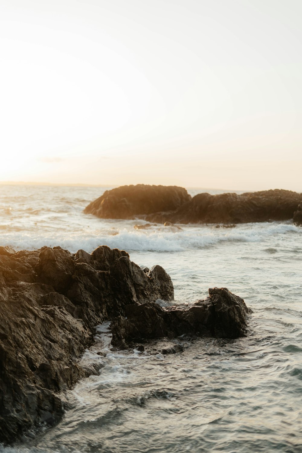 a person standing on a rock next to the ocean