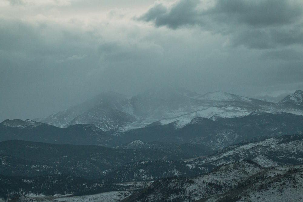 a mountain range covered in snow under a cloudy sky