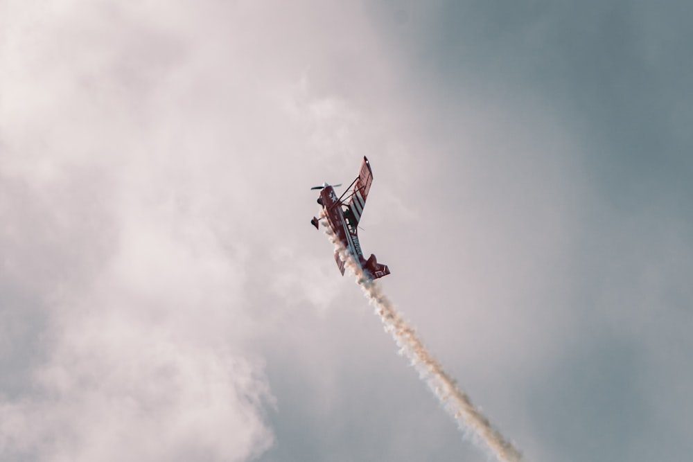 a red and white plane flying through a cloudy sky