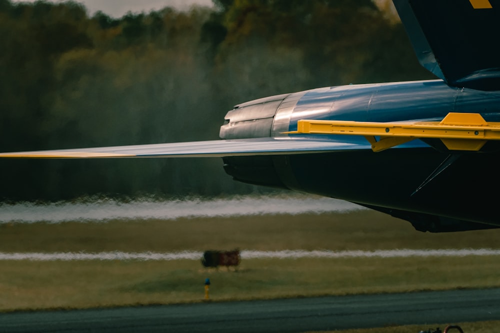 a blue and yellow plane is taking off from the runway