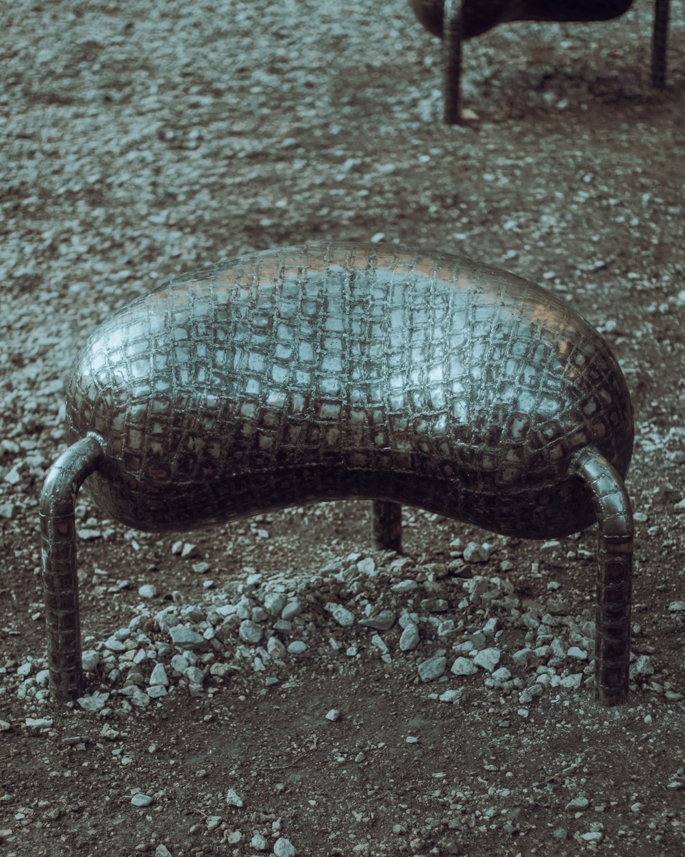 a metal bench sitting on top of a dirt field