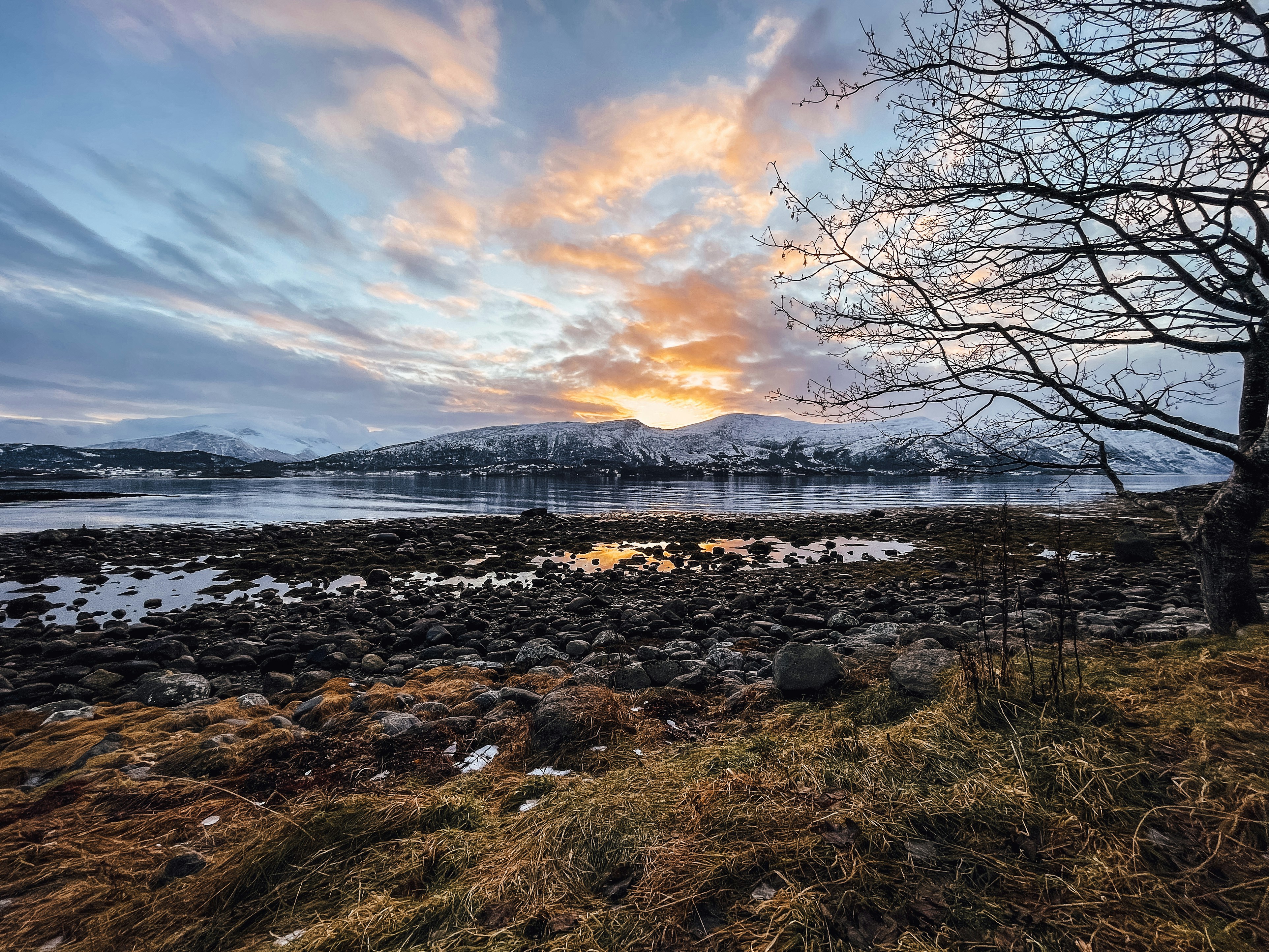 Spectacular sunset over the mountains and calm waters surrounding the Ålesund archipelago in Norway