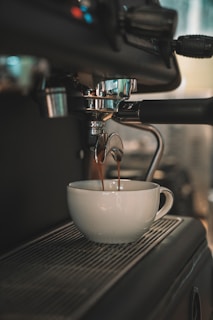 a cup of coffee being poured into a white bowl