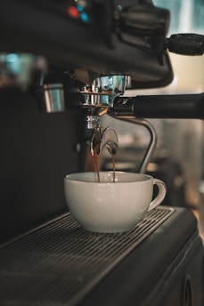a cup of coffee being poured into a white bowl