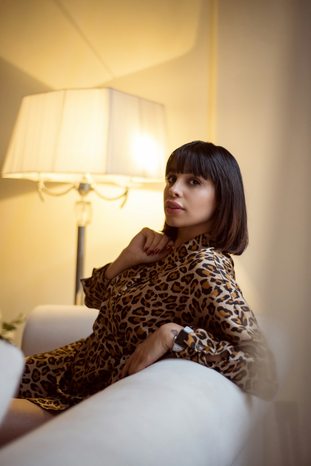 a woman sitting on a couch next to a lamp