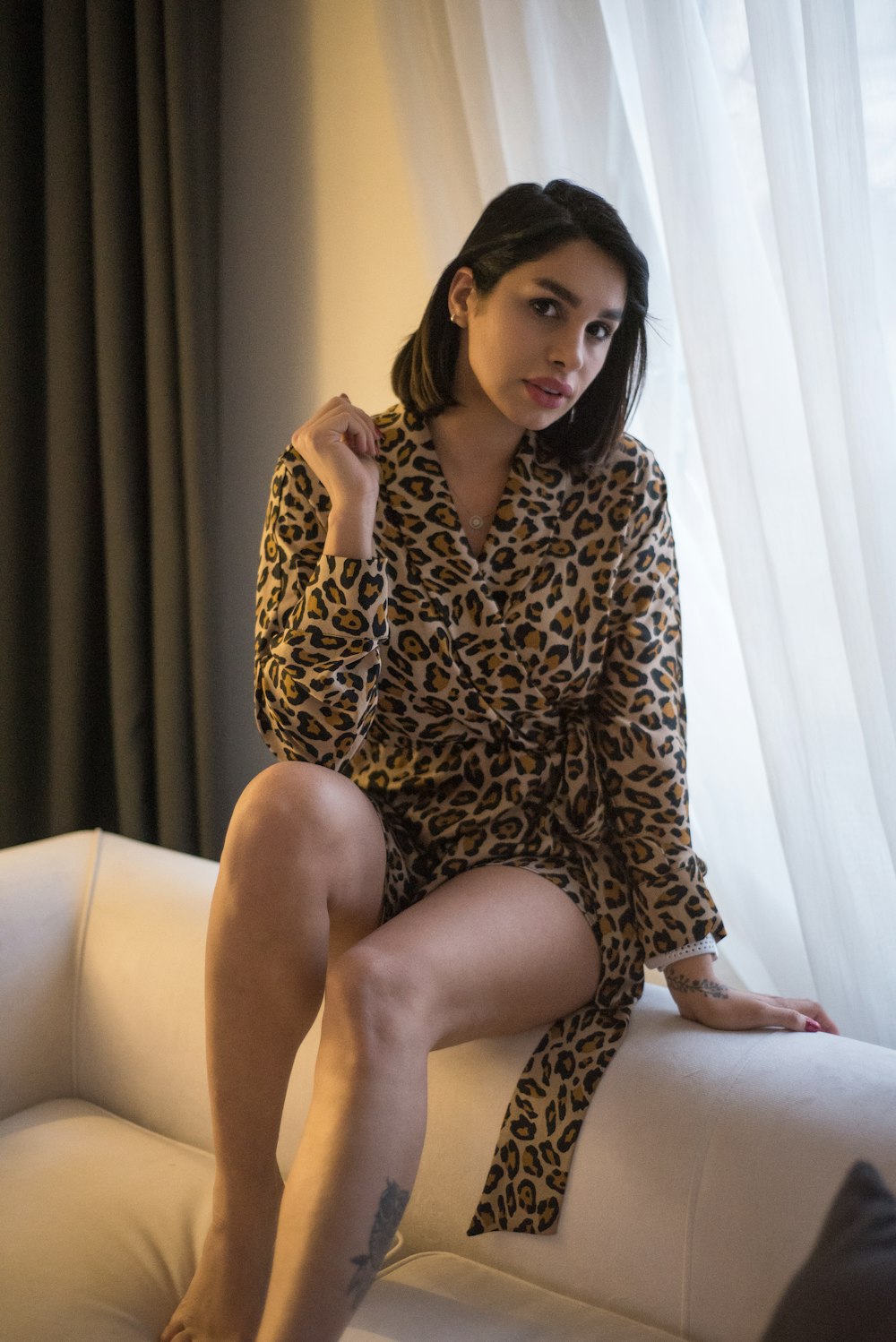a woman sitting on a couch wearing a leopard print robe