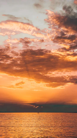 A vibrant sunset over the calm sea with a fishing boat preparing for an offshore expedition.