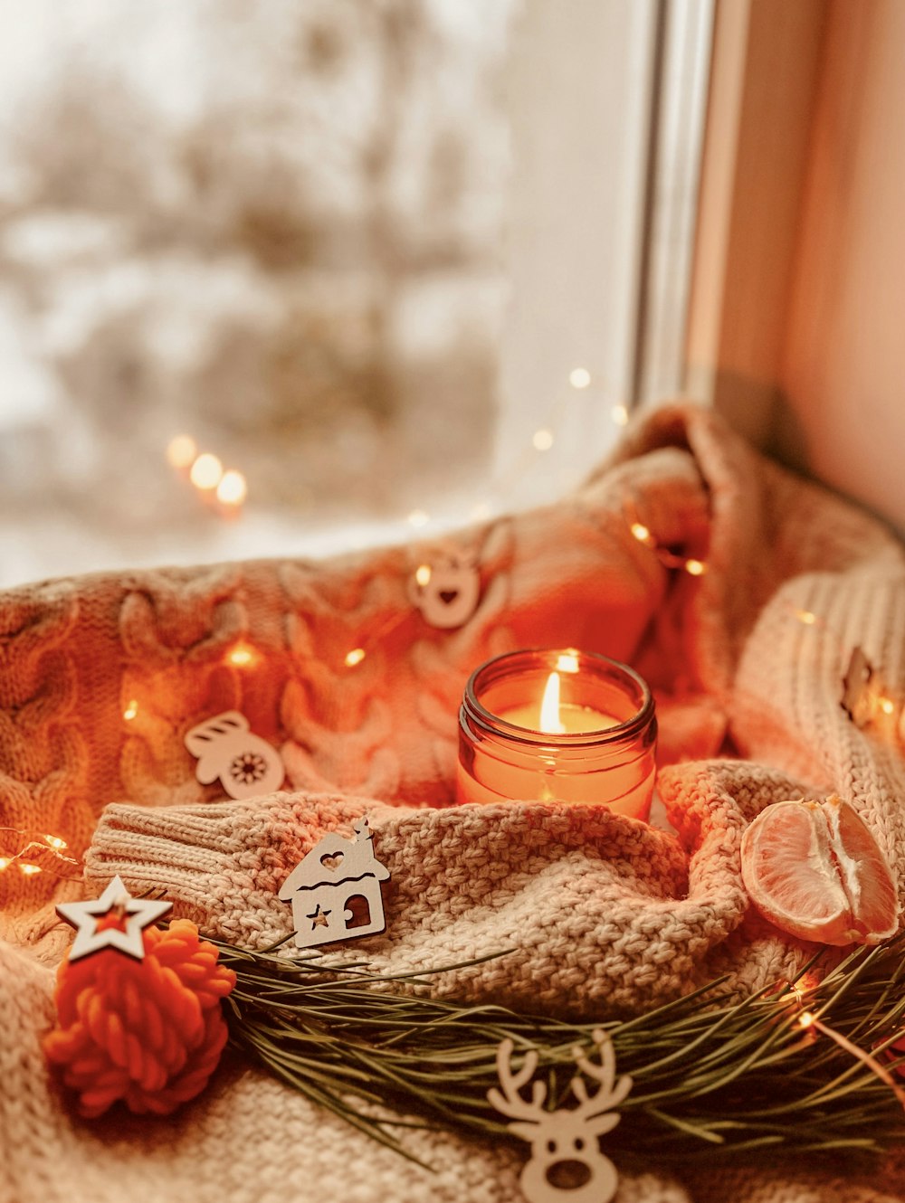 a lit candle sitting on top of a blanket next to a window