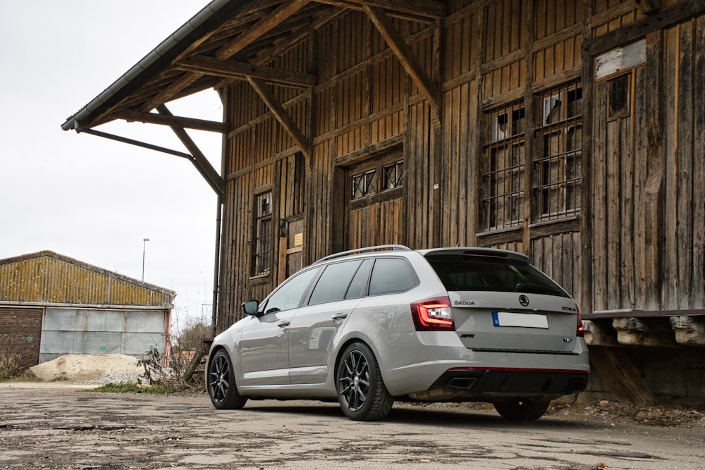 a white car parked in front of a wooden building