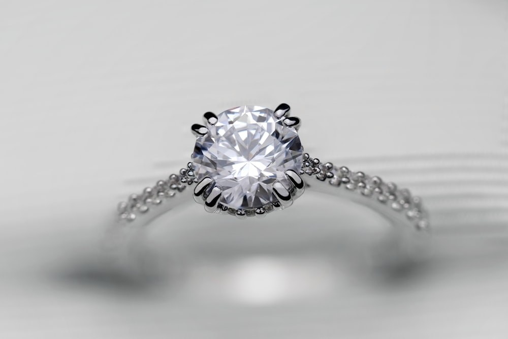 a close up of a diamond ring on a white surface