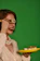 Close-up of a smiling woman holding a beautifully presented sweet sushi plate in a cozy kitchen