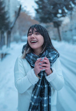 a woman standing in the snow with a scarf around her neck