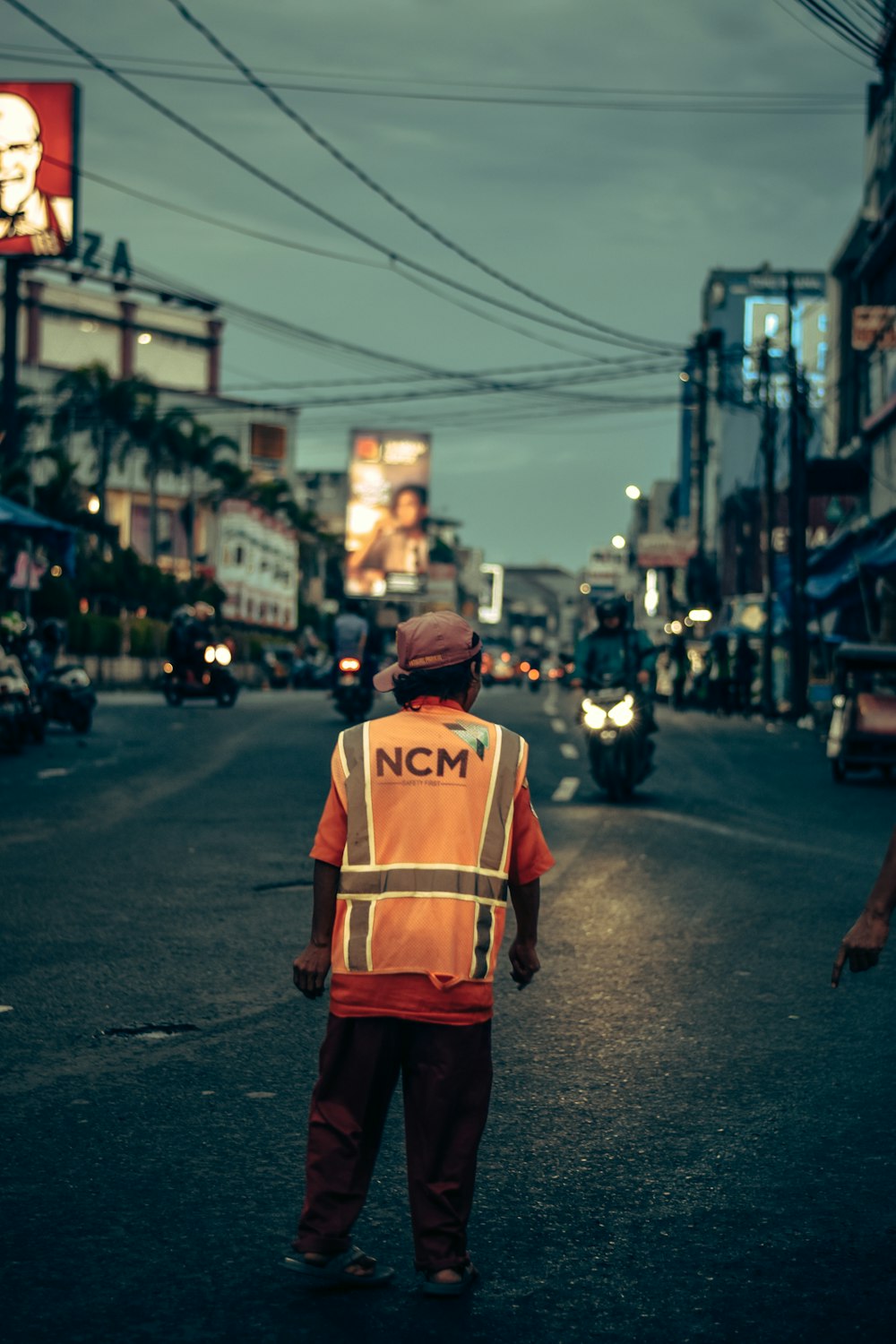 a man in an orange vest is walking down the street