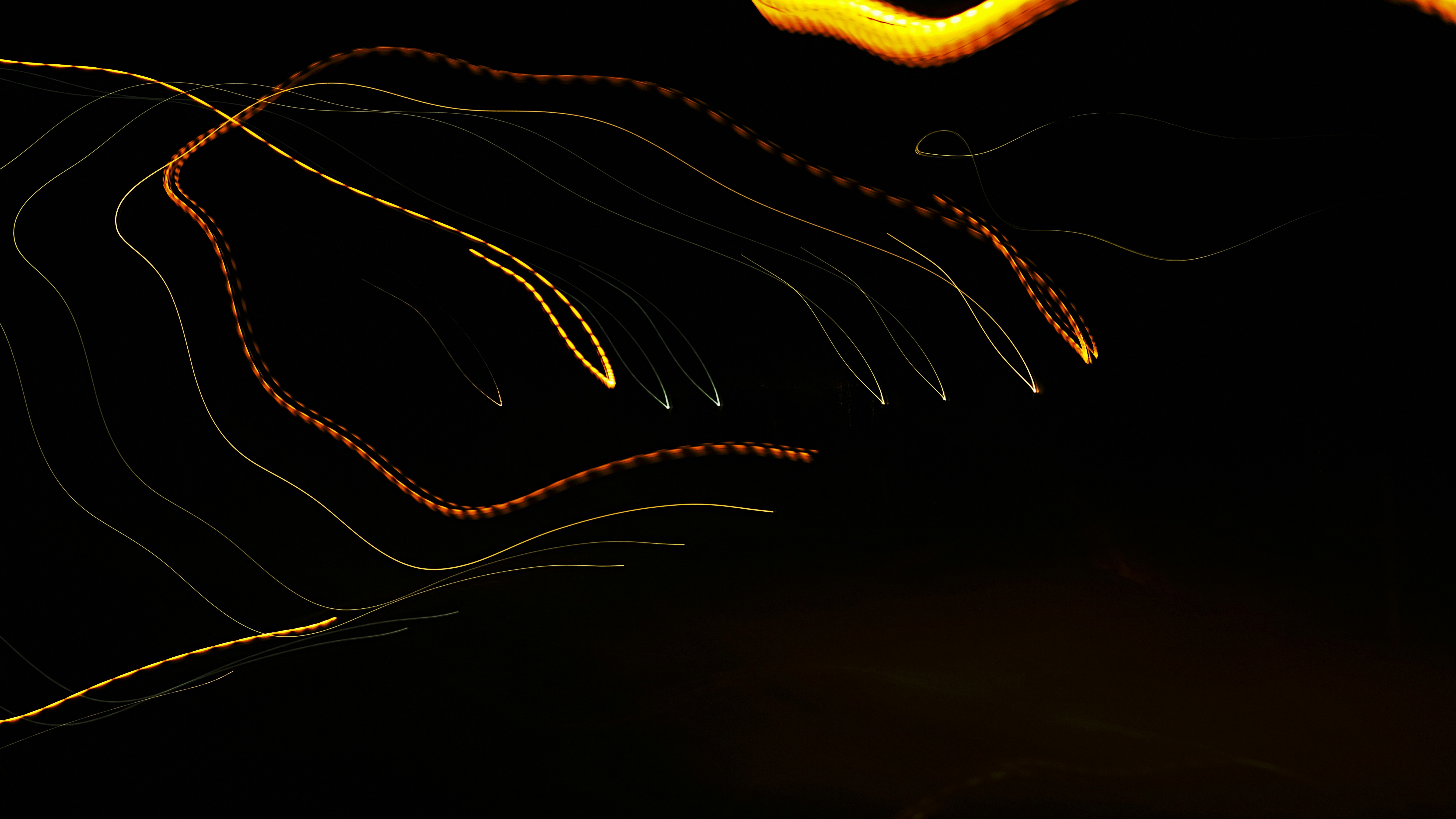 a blurry photo of a street light at night, Several yellow, orange, and light green streaks of light traveling downward.