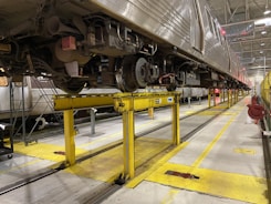 Workshop technician repairing a freight railcar under bright industrial lights