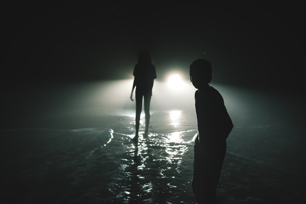 two people standing in the water at night