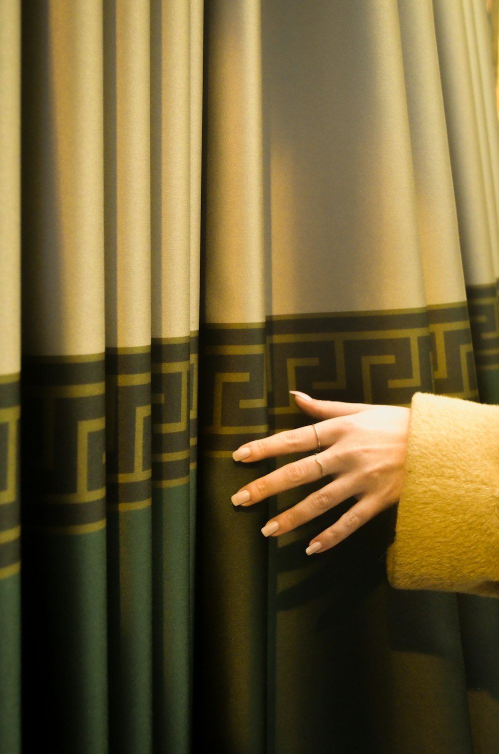 a woman's hand with a towel on top of a curtain