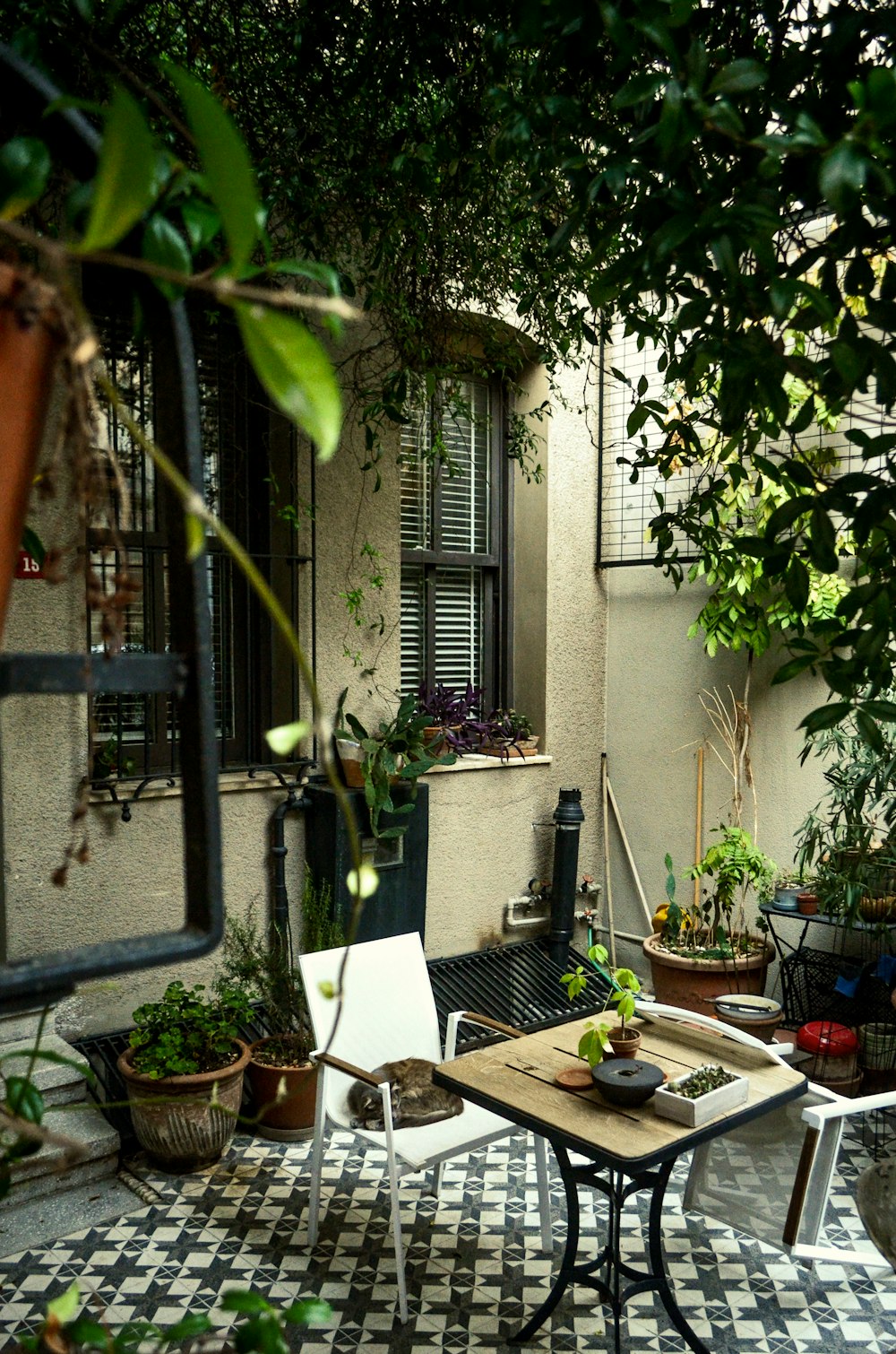 a patio with a table, chairs and potted plants