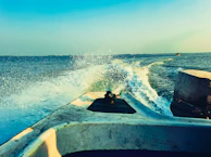 A powerful motorboat cutting through crystal-clear blue waters on a bright day.