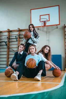 A warm, inviting photo of a diverse group of women gathered around a basketball court, sharing stories and laughter.