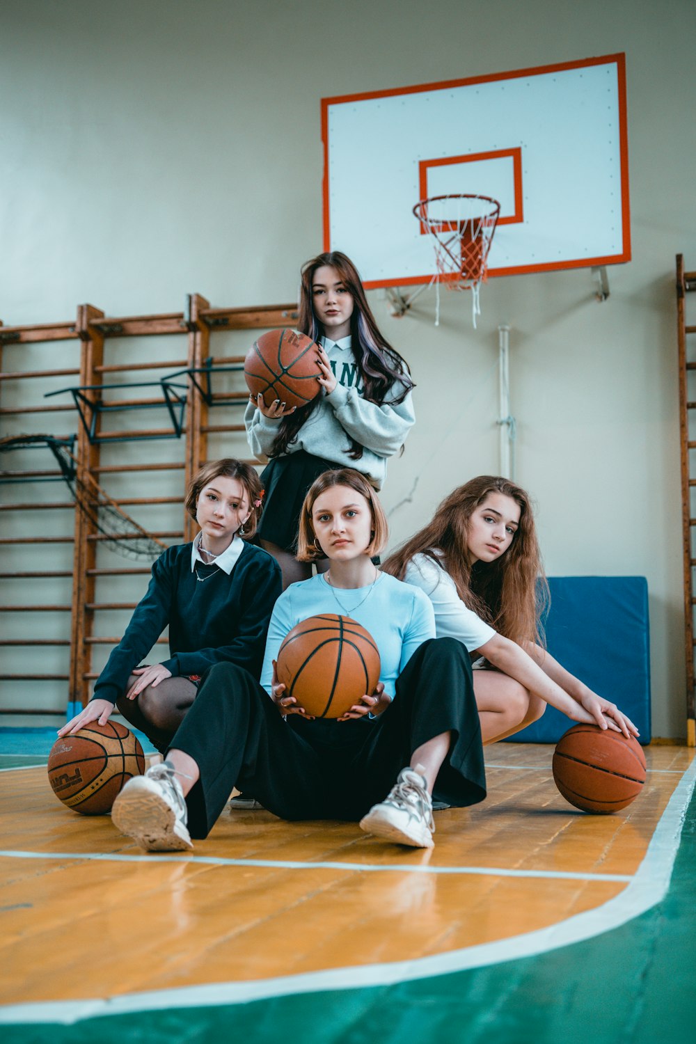 a group of young women sitting on top of a basketball court
